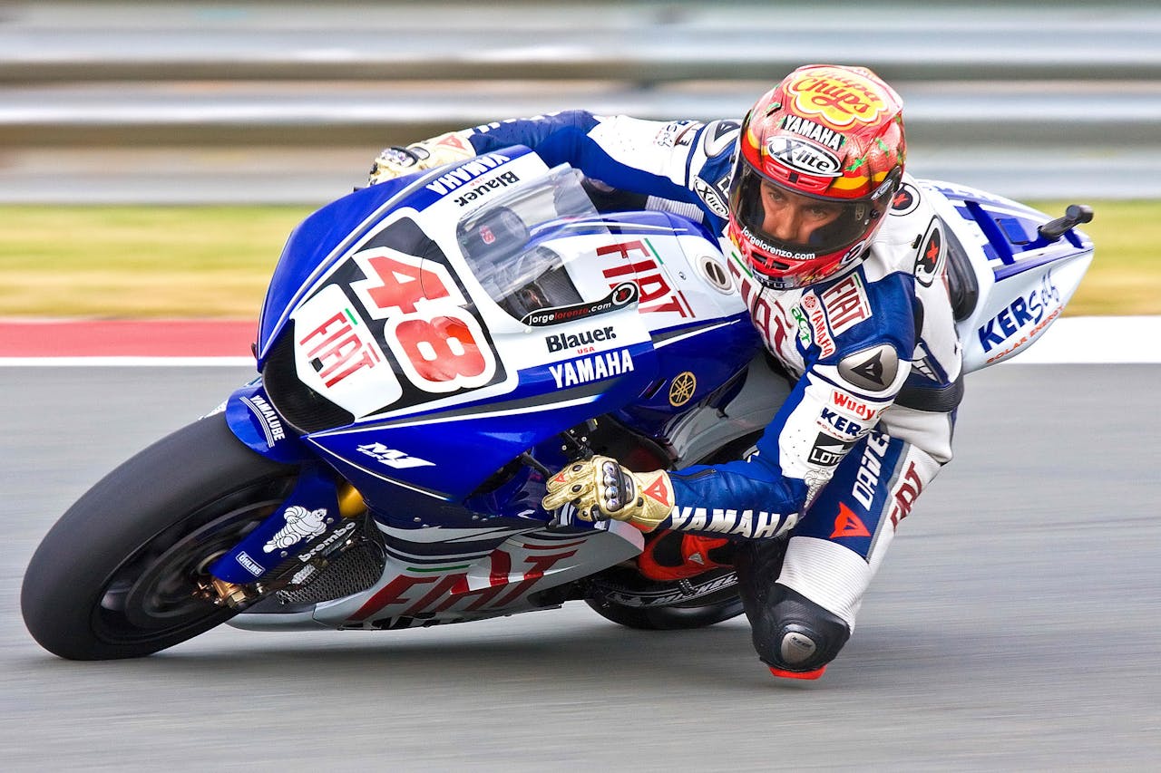 A Yamaha sports bike speeds through a race track, showcasing motorsport excitement.